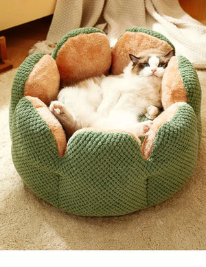 Ragdoll cat sleeping inside a green flower-shaped plush pet bed on a beige carpet.