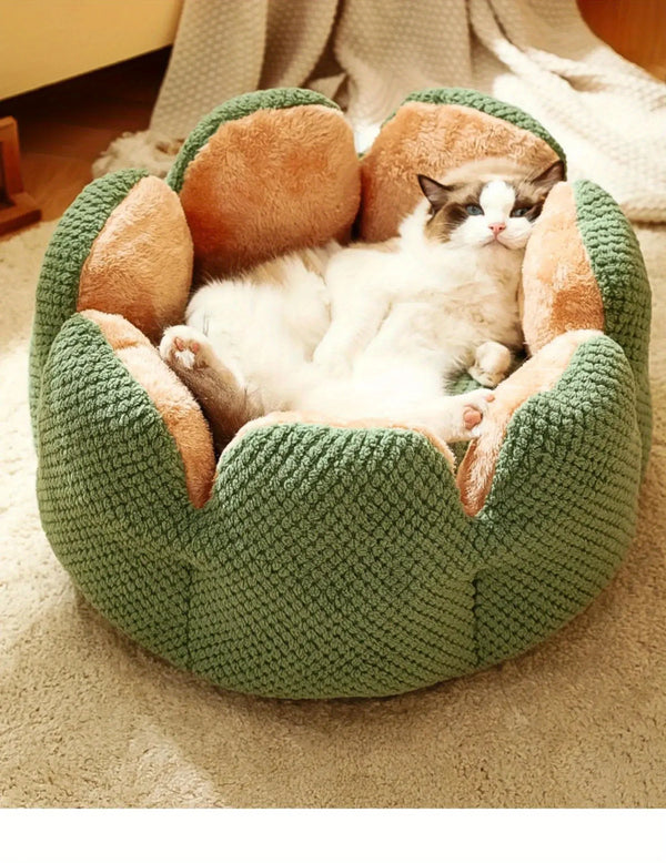 Ragdoll cat sleeping inside a green flower-shaped plush pet bed on a beige carpet.