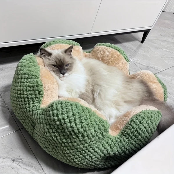 Long-haired cat resting inside a green flower-shaped plush pet bed on a tiled floor.