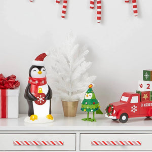 Decorative Christmas scene with penguin, tree, and truck on a shelf.