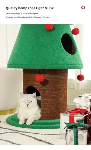 Cat sitting inside a green and brown cat house with red balls, surrounded by Christmas decorations.