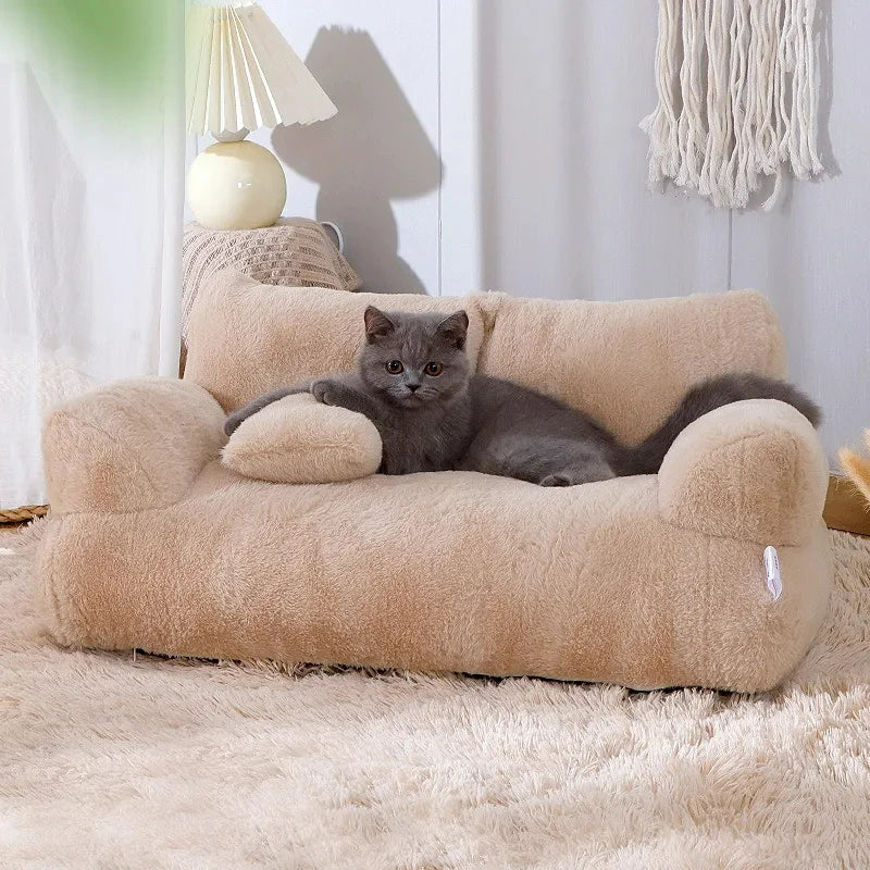 Gray cat relaxing on beige plush cat bed sofa with backrest and side pillows, cozy winter nest for cats and small dogs in a modern home setting.