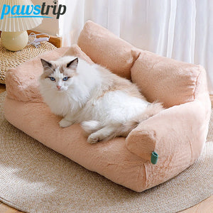Fluffy white cat lying on peach plush cat bed sofa with backrest and side pillows, cozy winter nest for cats and small dogs.