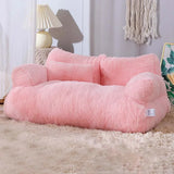 Pink plush cat bed sofa with backrest and side pillows, cozy winter nest for cats and small dogs in a modern living room setting.