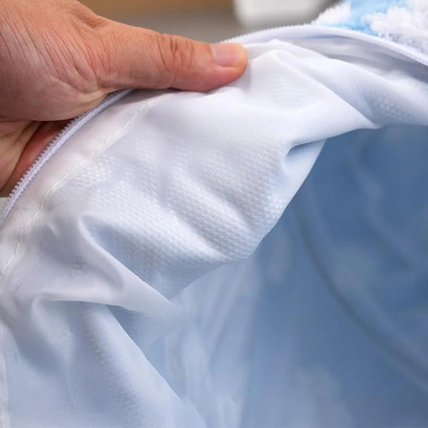 Close-up of a hand holding white fabric with a blue object partially visible.
