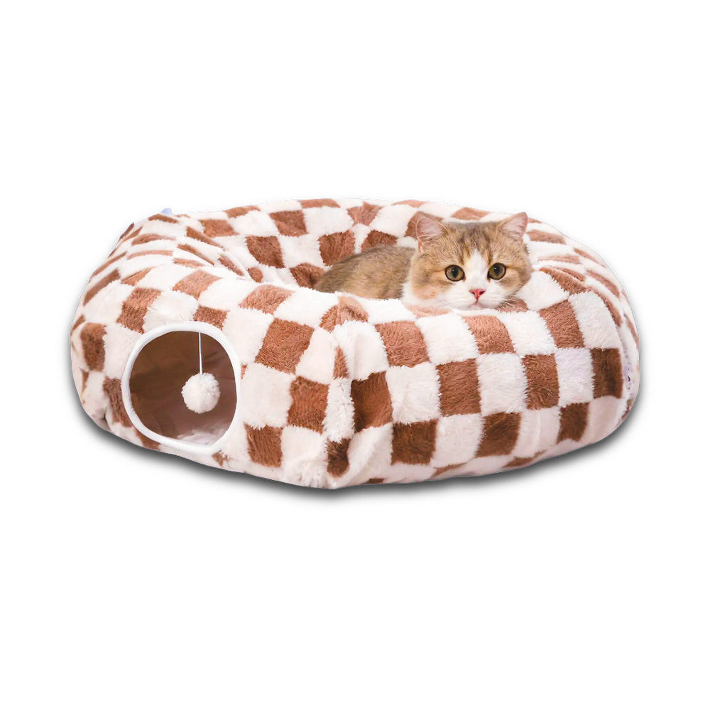 Brown and white checkerboard donut cat tunnel cave bed with hanging toy ball for indoor cats, styled under a decorated Christmas tree