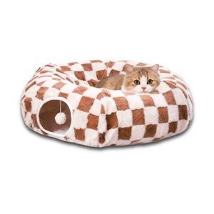 Brown and white checkerboard donut cat tunnel cave bed with hanging toy ball for indoor cats, styled under a decorated Christmas tree