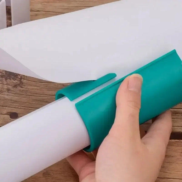 Hand using teal gift wrapping paper cutter to slice clean edges on a wrapping paper roll over wooden table — safe and precise holiday cutting tool