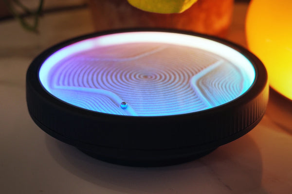 LED zen sand lamp with blue and warm gradient light creating circular sand patterns on a desk with soft ambient lighting