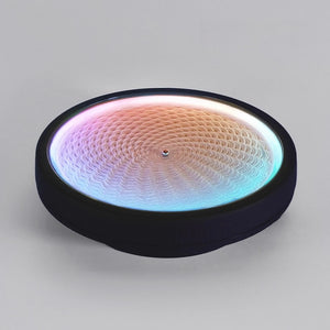 Round LED zen sand lamp on white surface with intricate iridescent sand pattern glowing in pink, gold and blue tones